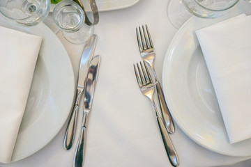 Table setting in light colors. Two snack knives and forks near plate with towel on white tablecloth.Photo for party, wedding or other special occasion. Restaurant business and service industry concept