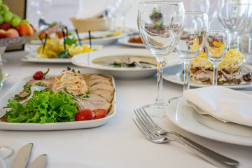 beautiful table setting in light colors with dishes and assorted food on a table with a white tablecloth for a party, wedding or other special event. Restaurant business and service industry concept.