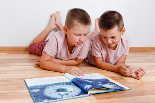 children lie on the floor and read a big book