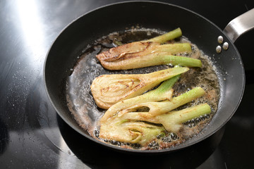 Sauteed fennel vegetable in brown butter in a cooking pan on a black stove, homemade vegetarian...