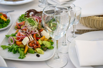 Beautiful table setting in light colors with dishes and assorted food on a table with a white tablecloth for a party, wedding or other special event. Restaurant business and service industry concept.