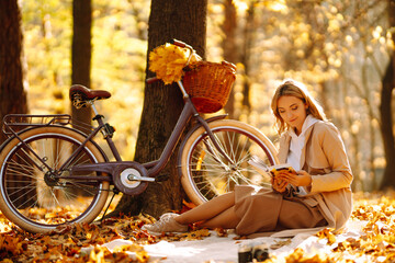 Stylish woman reading a book in the autumn park. Relaxation, enjoying, solitude with nature.