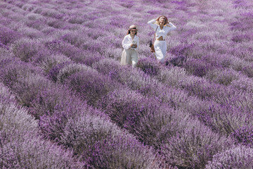 A young woman and her teendage daugher are enjoying a bright sunny day in the field of blooming lavender