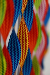 A shallow depth of field macro image of colorful ribbons with only yellow and green stripe ribbon in focus with blur foreground and background as abstract
