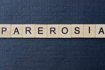  gray word parerosia from small wooden letters on a black table