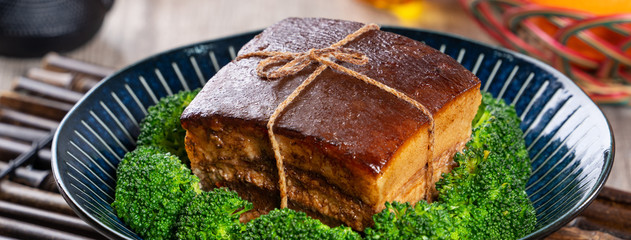Dong Po Rou (Dongpo pork meat) in a beautiful blue plate with green broccoli vegetable, traditional festive food for Chinese new year cuisine meal, close up.