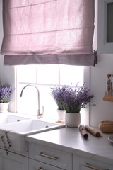 Beautiful lavender flowers on countertop near sink in kitchen