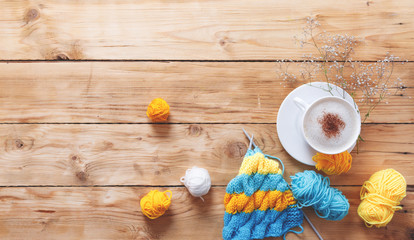 Yarn in warm colors on a white wooden board. Yellow, blue, beige, white and green. The beginning of the process of knitting a women's sweater. Female hobbies, knitting.