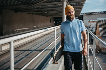 Fototapeta na wymiar Handsome young stylish hipster guy with beard with a longboard