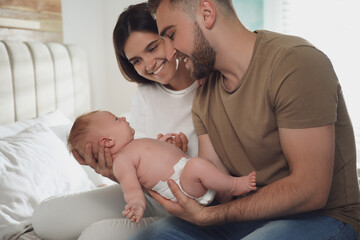 Obraz na płótnie Canvas Happy couple with their newborn baby at home