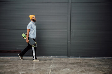 Handsome young stylish hipster guy with beard with a longboard