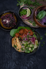 Vegan asian bowl with seitan, okra, chickpea flour omelette, pickles over brown rice and quinoa on dark background, copy space