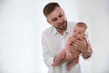 Father with his newborn son on light background