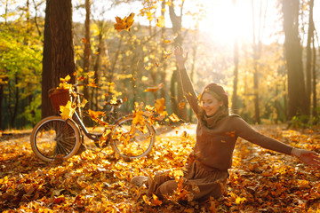Beautiful Woman throws up autumn leaves and having fun  in autumn park. Relaxation, enjoying, solitude with nature.