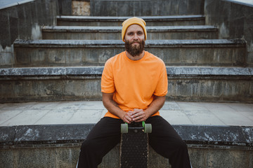 Handsome young stylish hipster guy with beard with a skateboard