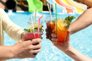 People with refreshing drinks in water park, closeup