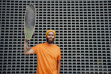 Handsome young stylish hipster guy with beard with a skateboard