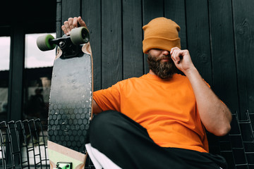 Handsome young stylish hipster guy with beard with a skateboard