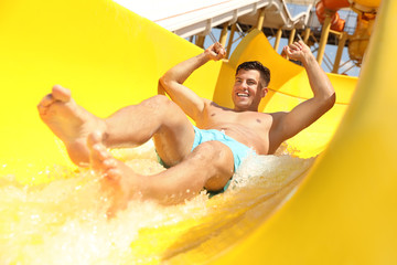 Man on slide at water park. Summer vacation