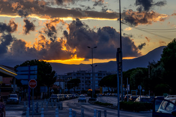 Cagnes-Sur-Mer, France 03.08.2020 Golden and dark clouds in the evening city. Heavenly dreamy fluffy colorful fantasy clouds. Summer time.
