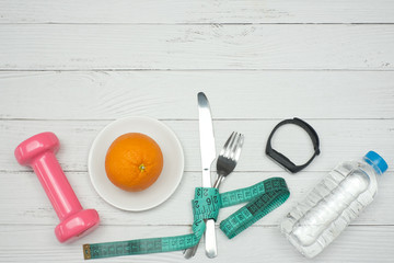 Top view medical and dieting concept on white wooden table background with orange fruit on plate, knife, fork, tape measure, drum bell, drink water, Flat lay with copy space