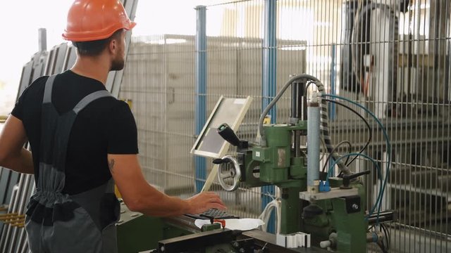 Young operator of industrial machine works in the factory.