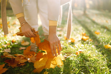 Fototapeta na wymiar Bright yellow autumn leaves in the woman hands. Young woman collects leaves in autumn park.