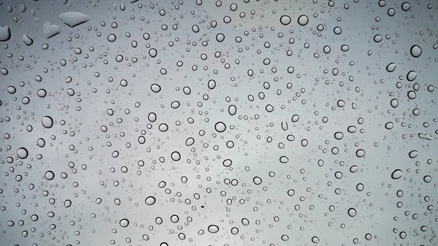  Rain droplets cling to the car glass at dusk. soft focus.