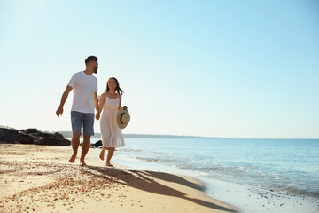 Happy young couple running on beach near sea. Honeymoon trip