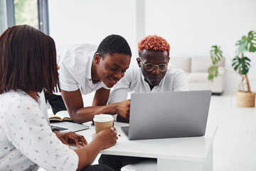 Fototapeta premium Concentrated at project by using laptop. Group of african american business people working in office together