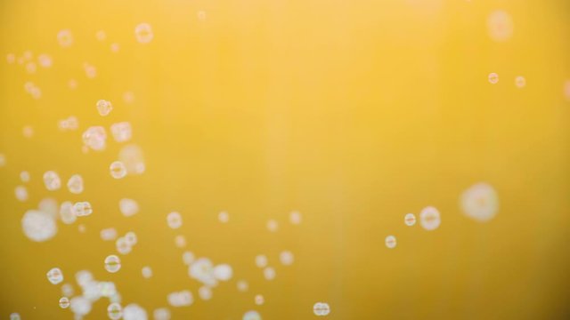 White soap bubbles flutter on a yellow background