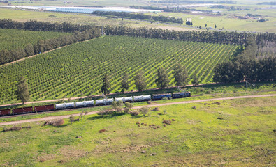 Cape Town, Western Cape / South Africa - 07/24/2020: Aerial photo of a train with vineyards in the background