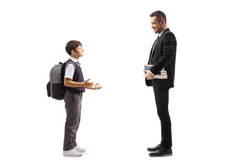 Schoolboy in a uniform standing and talking to a man in a suit with a pile of books