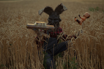 Man in image of sorcerer performs a voodoo ritual and holds doll impaled wire and old toy car.