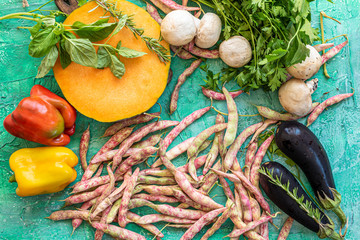 Angri, Italy. Composition of row vegetables on a green background with pumpkin, peppers, eggplant, mushrooms, fresh beans, parsley, basil and rosemary.