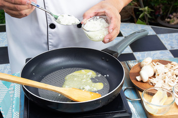 Chef putting minced onion in the pan prepared for cooking mushroom cream soup