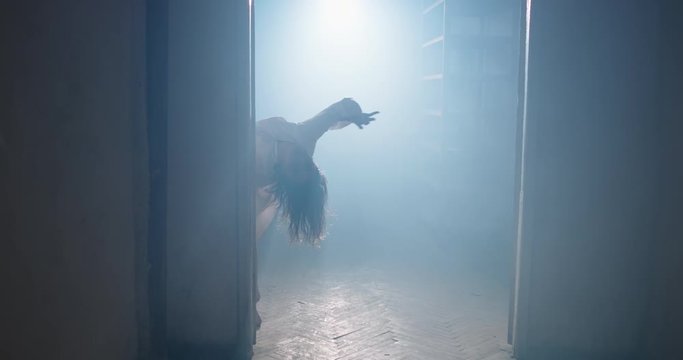 Creepy psycho girl in white smock agonizing and convulsing. Exhorcist lunatic crawling in hallway - halloween, horror movie 4k dynamic shot