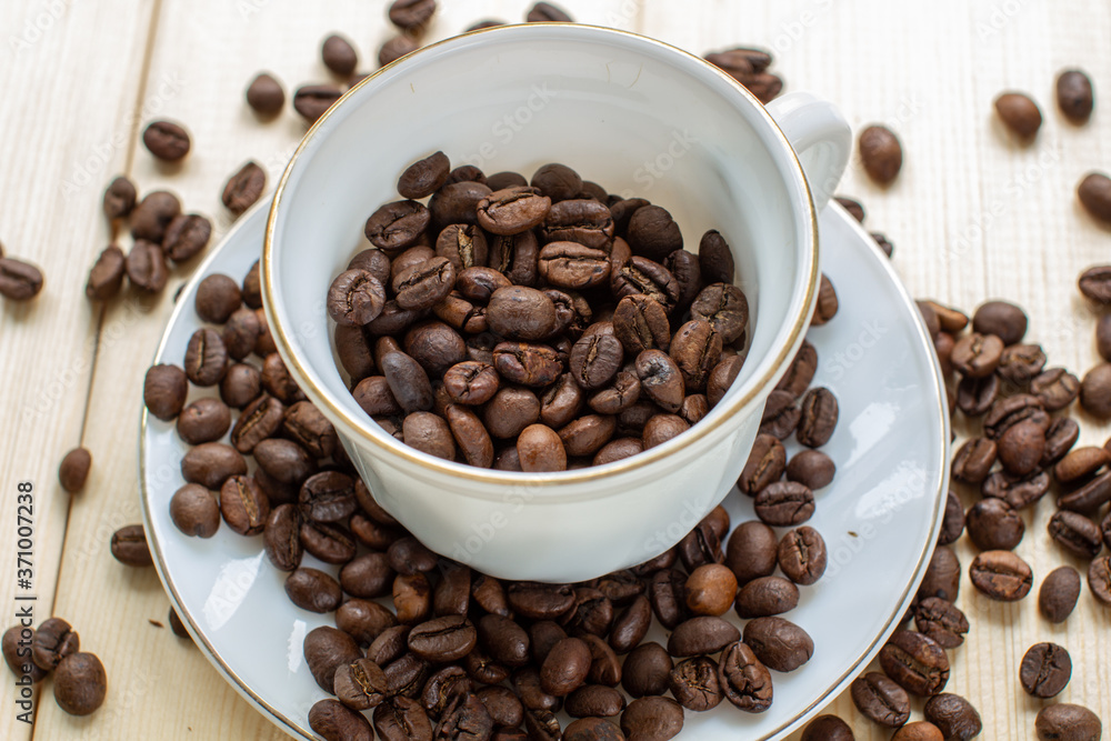 Poster white mug with cup of coffee beans on wooden background with selective focus and crop fragment