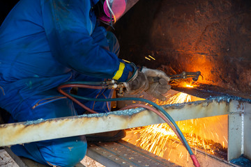 Worker cutting metal steels by Gas Cutting Torch. He cutting the iron plate in the confined spaced.