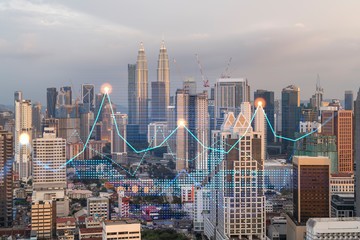 Market behavior graph hologram, sunset panoramic city view of Kuala Lumpur. KL is popular location to achieve financial degree in Malaysia, Asia. The concept of financial data analysis.
