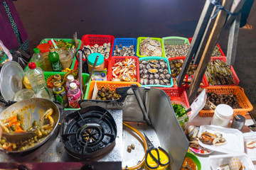 Vietnamese woman selling seafood on the counter and Snail's for sale in a night market in Ho Chi Minh city (Saigon), Vietnam. Food and drink concept
