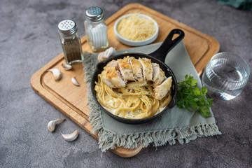 Alfredo pasta dinner with creamy white sauce with herbs and sliced chicken