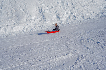 Joyful kid sledding down the hills on a winter day.