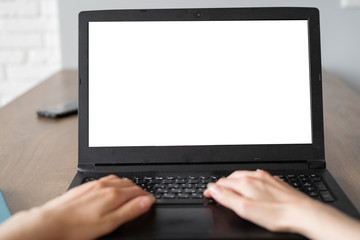 Laptop with blank screen on white table with blurred background as concept. two hands are typing...