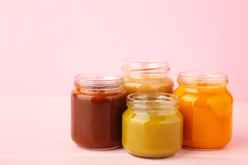 Jars of baby puree on pink background. Fruit and vegetables puree