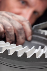 Technician with dirty hand rasping a gear wheel