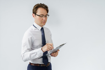 Portrait of a businessman who stands and writes down on a tablet. White background.