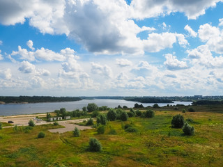 photo of a large field next to a river above a cloudy sky
