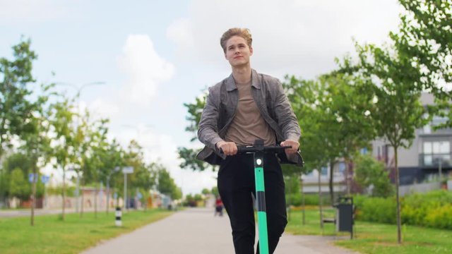business and people and concept - young man or teenage boy riding electric scooter outdoors