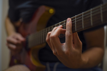 Fototapeta na wymiar Close up of man's hands playing electric guitar. Musical instrument for recreation or hobby passion concept.